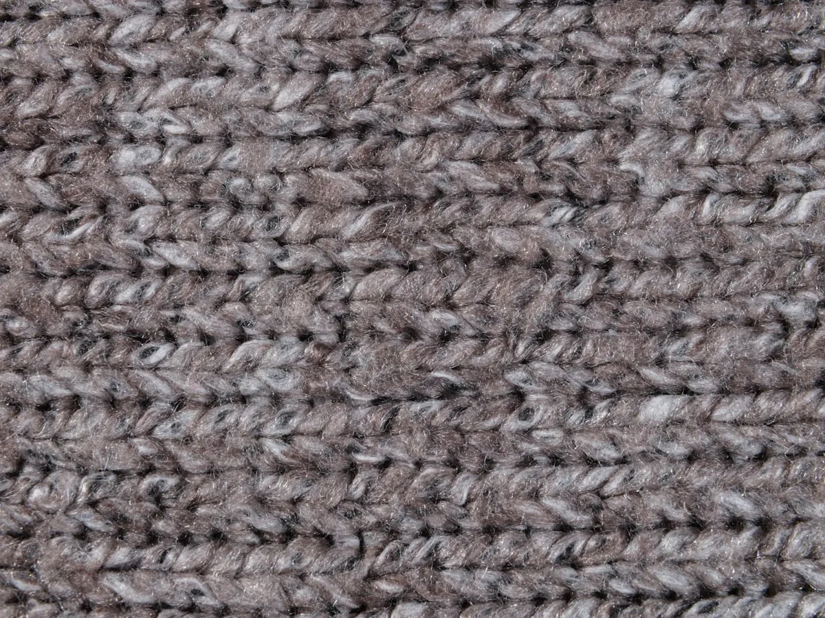 Close-up of a grey chunky-knit wool texture, showing thick individual strands and visible stitch structure.