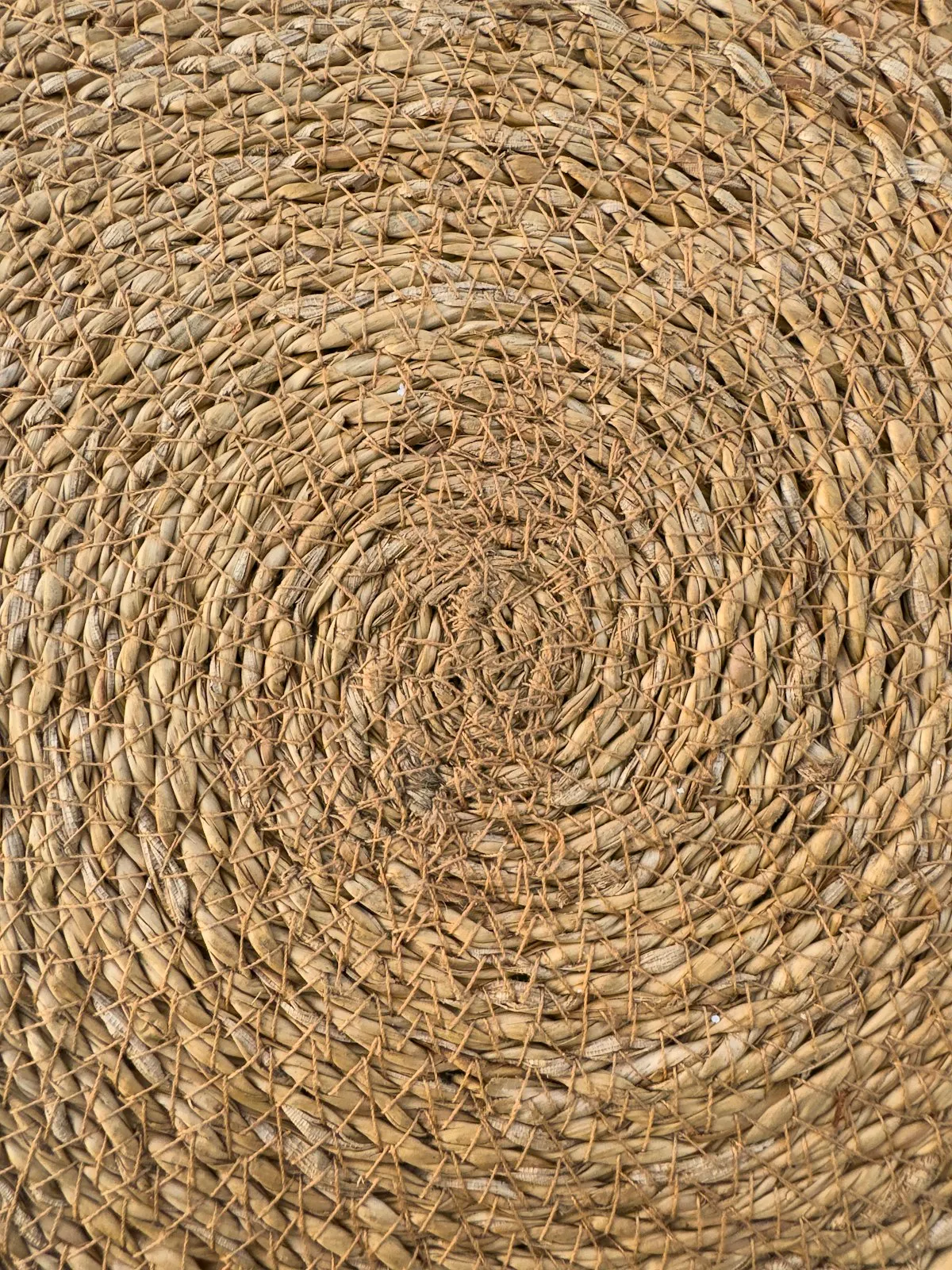 Overhead close-up of a spiral-woven natural fibre rug, showing concentric rings of braided jute cord.